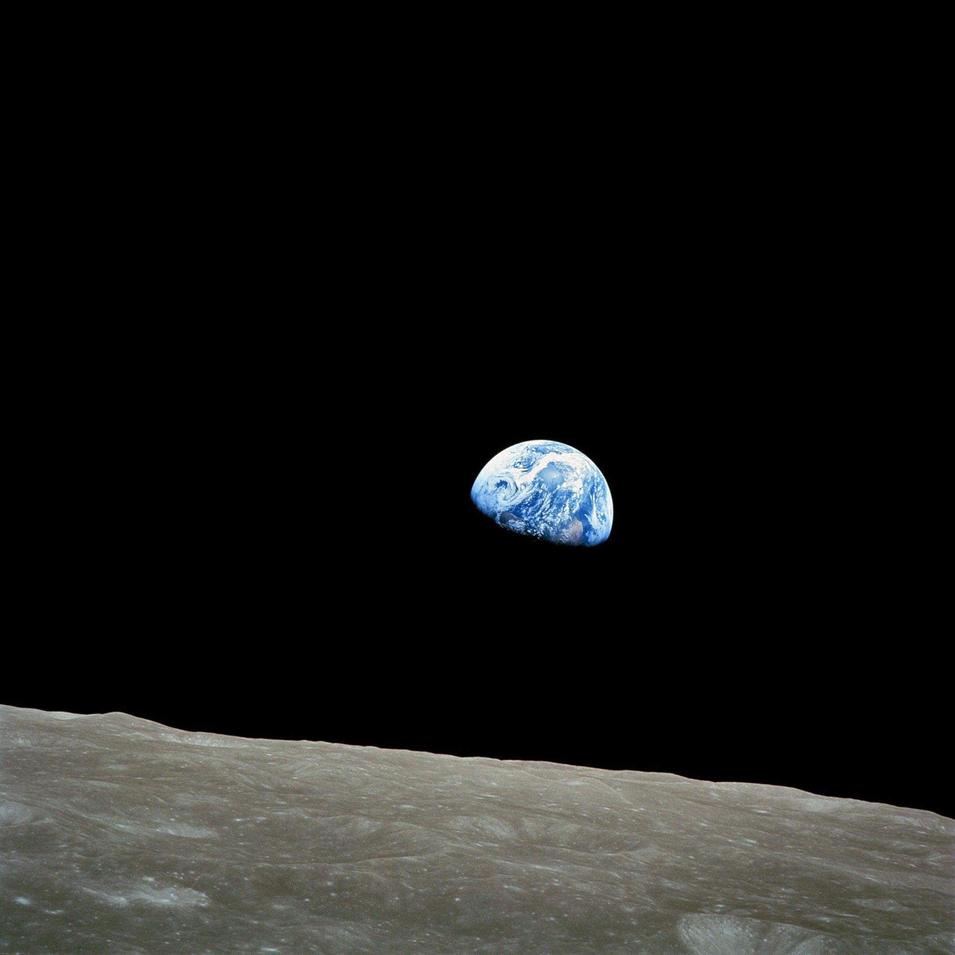 La Terra sorge all’orizzonte sopra la superficie lunare, vista dallo spazio profondo: un’immagine iconica che mostra il nostro pianeta fragile e luminoso sospeso nel buio cosmico, simbolo dell’era Apollo e del cambiamento di prospettiva dell’umanità sull’
