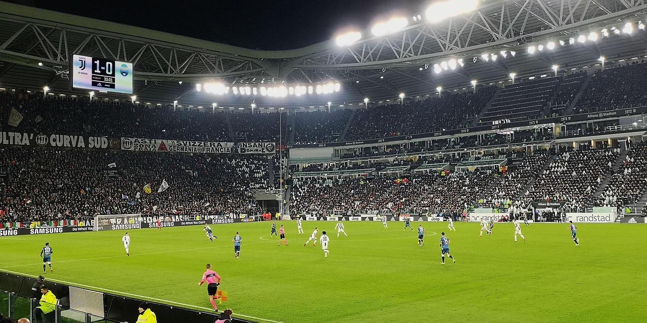 Stadio Allianz Stadium durante una partita della Juventus, con il pubblico sugli spalti e i giocatori in azione sul terreno di gioco